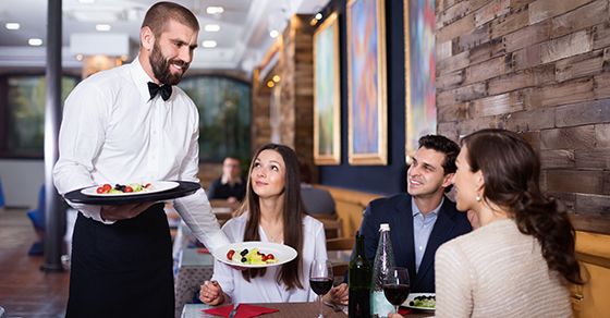 Waiter delivering plated food to couple sitting at a table